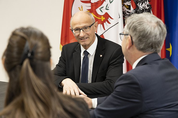 LH Mattle am Tisch sitzend von vorne fotografiert und Finanzminister von Brunner von hinten zu sehen.