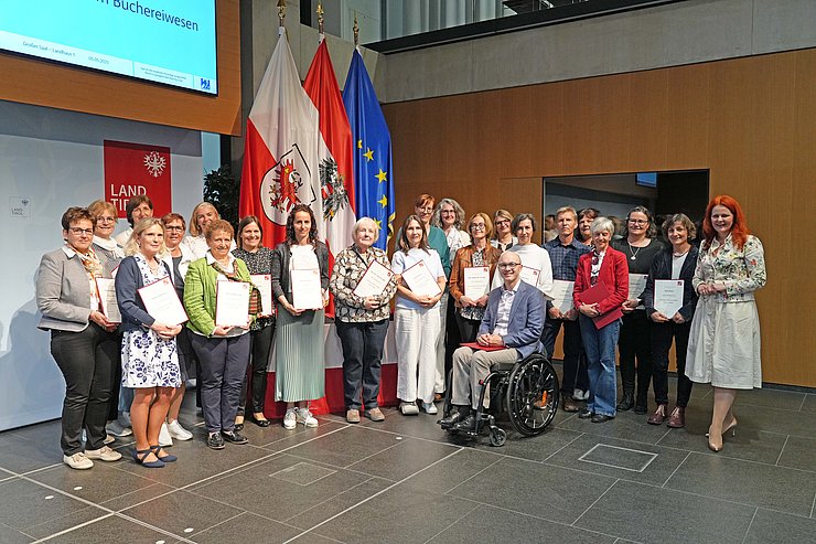 © Land Tirol/Reiter Mehrere Menschen posieren vor Flaggen.