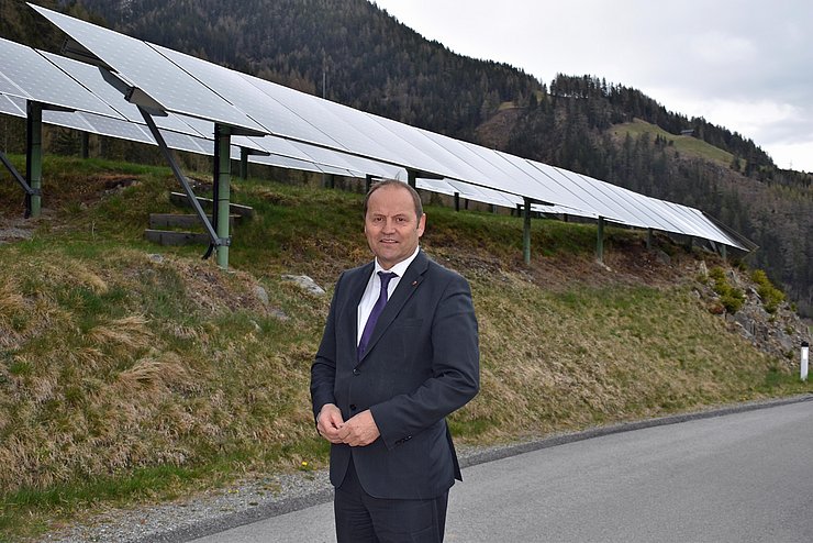 LHStv Josef Geisler steht vor PV-Anlage. Tirol wechselt beim PV-Ausbau auf die Überholspur. LHStv Josef Geisler kündigt weitere Erleichterungen für gebäudenahe PV-Anlagen und kleinere Freiflächenanlagen an. Neun von zehn PV-Anlagen sind künftig anzeigen- und bewilligungsfrei. 