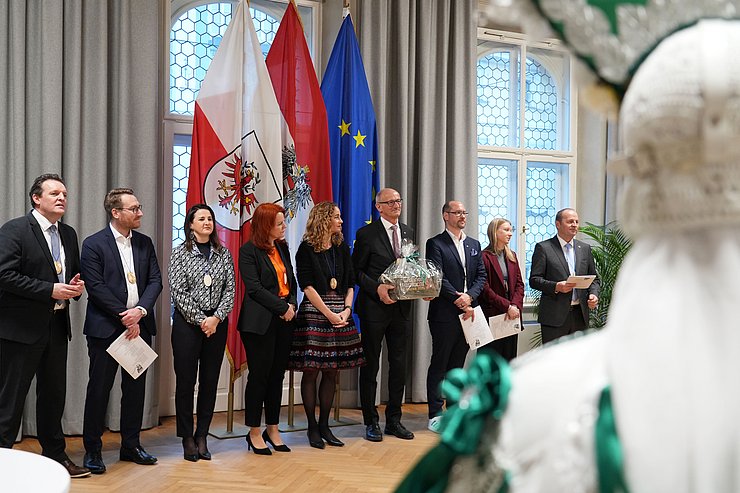 Die gesamte Tiroler Landesregierung nebeneinander, wie sie den Figuren beim Auftritt zusehen.