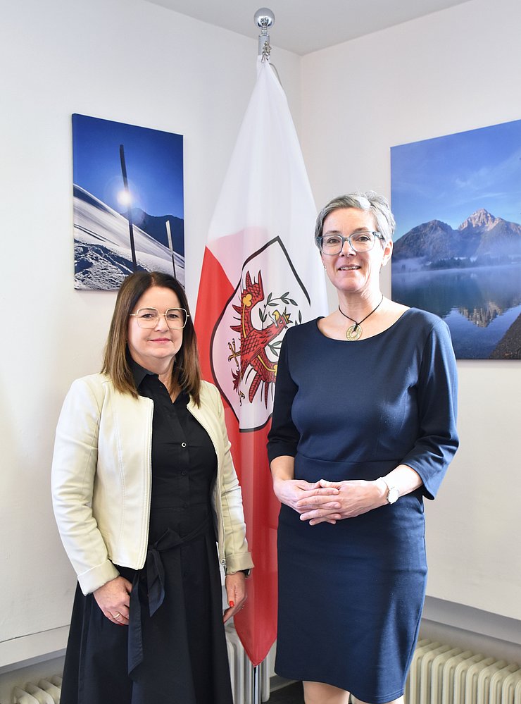 Hochformataufnahme von zwei Frauen vor einer Fahne.