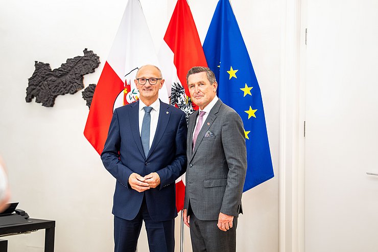 © Land Tirol/Christanell Zwei Menschen posieren vor mehreren Flaggen.