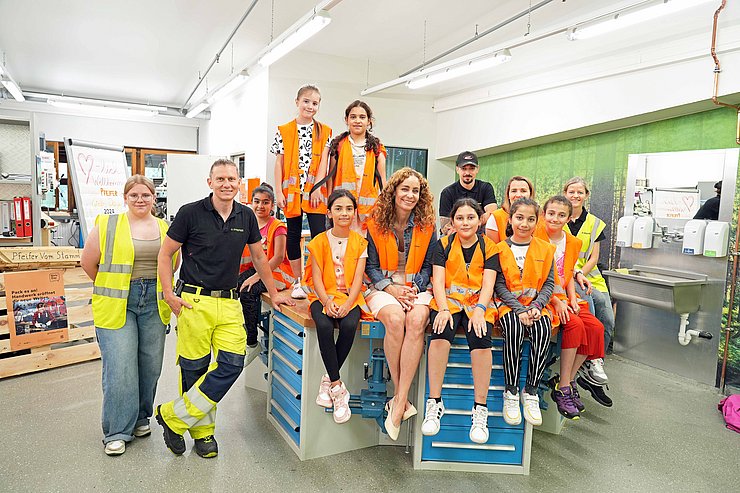 Gruppenbild mit Landesrätin Pawlata und einer Schulklasse vor einer Werkbank.
