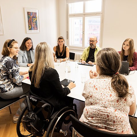 Menschen um Tisch sitzend