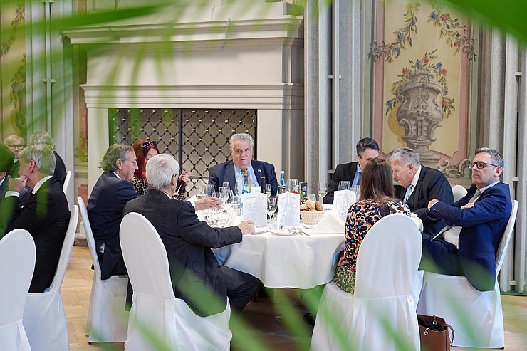 Mehrere Personen sitzen an einem Tisch und unterhalten sich.