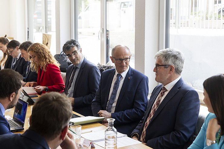 © Land Tirol/Die Fotografen Mehrere Menschen sitzen an einem Tisch und reden bzw. schreiben.