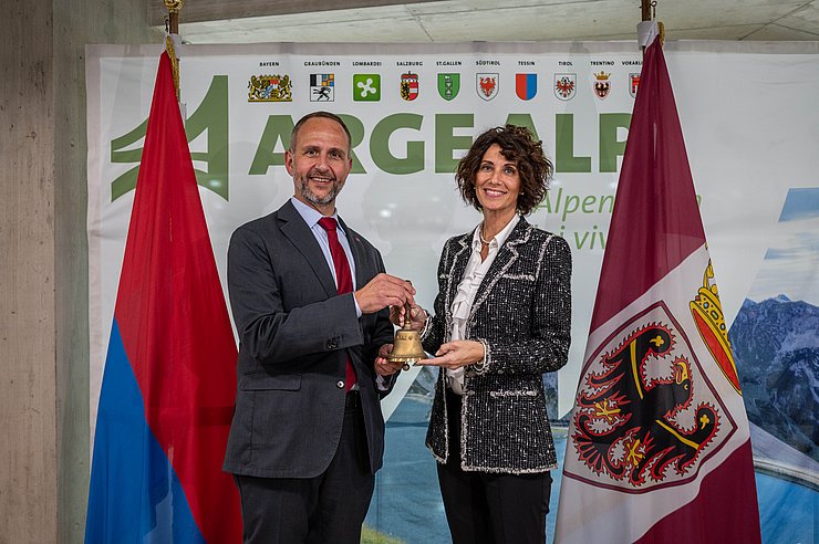 © Kanton Tessin Personen stehen nebeneinander, halten Glocke