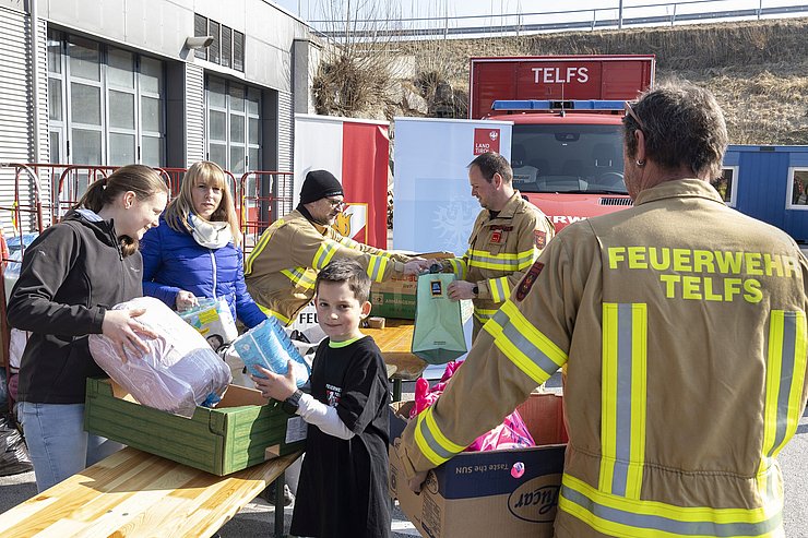 © Land Tirol/Die Fotografen Feuerwehr und Menschen, die Güter annehmen.