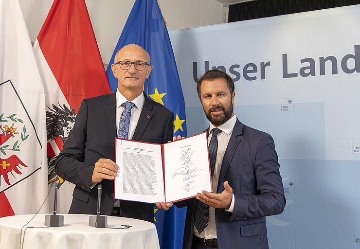 LH Anton Mattle und LHStv Georg Dornauer halten bei der Pressekonferenz die neue Tirol-Erklärung in den Händen.