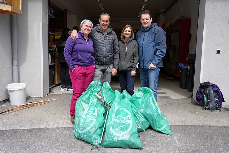Personen stehen nebeneinander mit gefüllten Müllsäcken