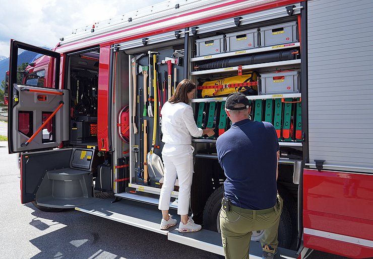 Mair vor Feuerwehrauto; schaut sich Ausrüstung an