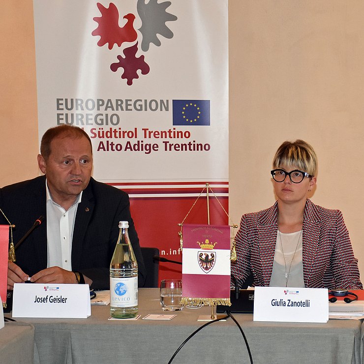 © Land Tirol Bei einem Treffen der Europaregion sitzen an einem Tisch mit grauer Tischdecke von links LHStv Geisler und LRin Zanotelli.