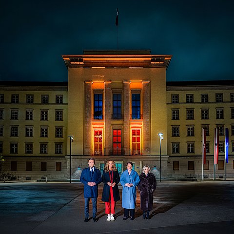 Landtagspräsidentin Sonja Ledl-Rossmann (3.v.li.), Vizepräsidentin Elisabeth Blanik (4.v.li.), Vizepräsident Dominik Mainusch und LRin Eva Pawlata vor dem orange beleuchteten Landhaus