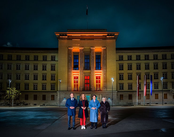 Landtagspräsidentin Sonja Ledl-Rossmann (3.v.li.), Vizepräsidentin Elisabeth Blanik (4.v.li.), Vizepräsident Dominik Mainusch und LRin Eva Pawlata vor dem orange beleuchteten Landhaus