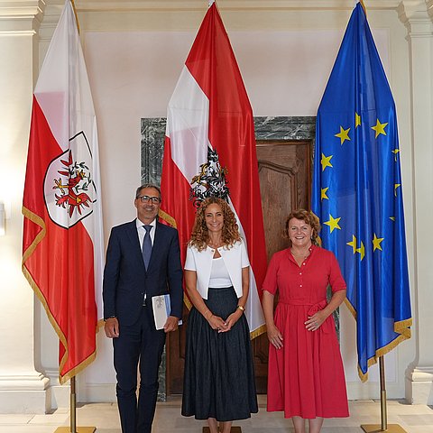 Personen stehen vor Fahnen