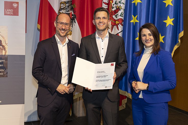 drei Personen mit Urkunde