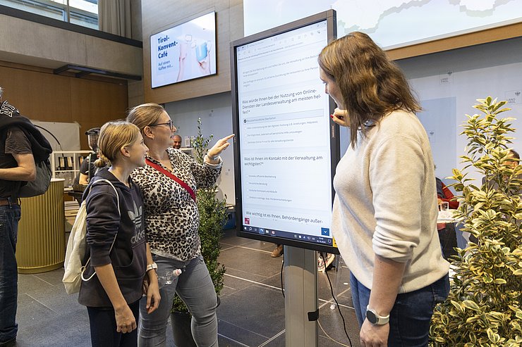 © Land Tirol/Die Fotografen Personen vor großem Bildschirm mit Fragen