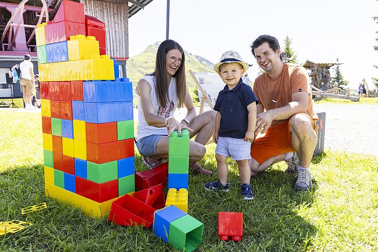 zwei Erwachsene und ein Kleinkind mit Riesen-Lego-Bausteinelstation