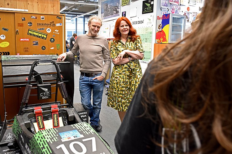Zwei Personen in einer Werkstatt im Gespräch mit einer weiteren Person