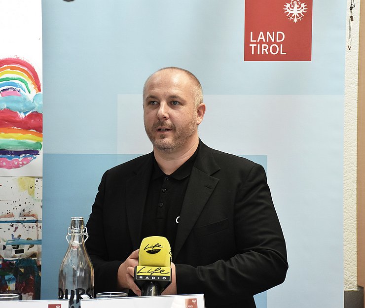 © Land Tirol/Hörmann Foto von einem Mann der bei der Pressekonferenz spricht.