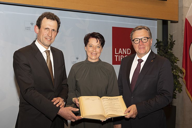 © Land Tirol/Die Fotografen v.li.: Christoph Grabenwarter (Präsident des Österreichischen Verfassungsgerichtshofes), Landtagspräsidentin Sonja Ledl-Rossmann und LH Günther Platter mit dem Landesgesetz- und Verordnungsblatt, in dem die Landesordnung vor 100 Jahren verlautbart wurde.