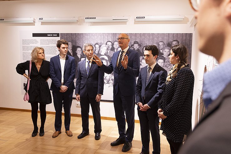 © Land Tirol/Die Fotografen Landeshauptmann Mattle steht mit der Familie Wisnicki in den Ausstellungsräumen.