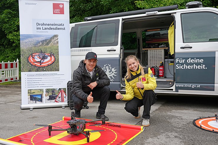 © Land Tirol/Reiter Zwei Menschen posieren vor einer Drohne.
