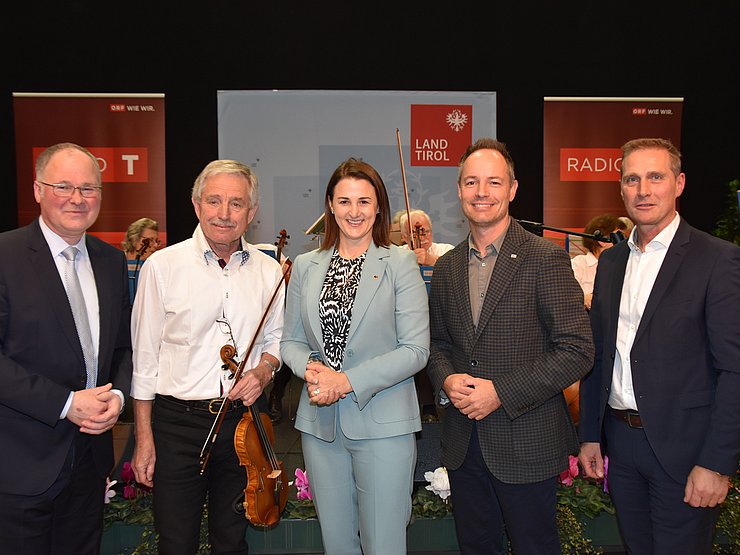 © Land Tirol/Schwarz Vor einem Orchester in der Messe Innsbruck stehen von links Congress-Messe-Direktor Christian Mayerhofer, Wolfgang Niedermayr, Leiter des Salonorchesters Veldidena, LRin Astrid Mair, Markus Lassenberger, Vizebürgermeister Innsbruck, Franz Jirka, Wirtschaftskammer Tirol.