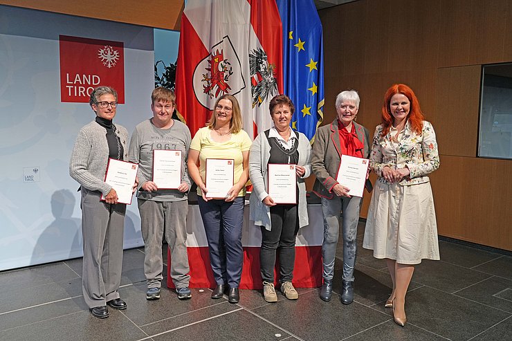 © Land Tirol/Reiter Mehrere Menschen posieren vor Flaggen.