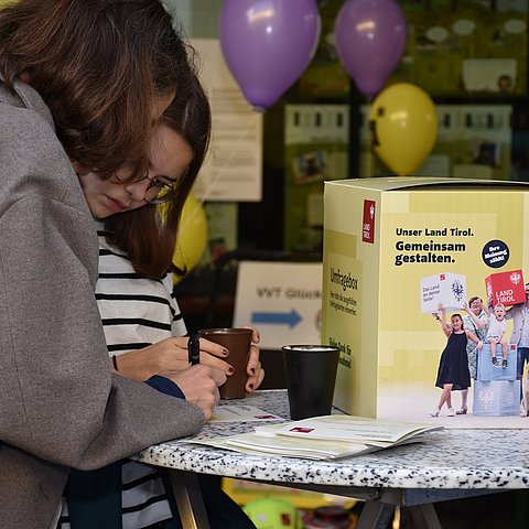 Zwei Kinder, die Umfrage ausfüllen neben Umfragebox