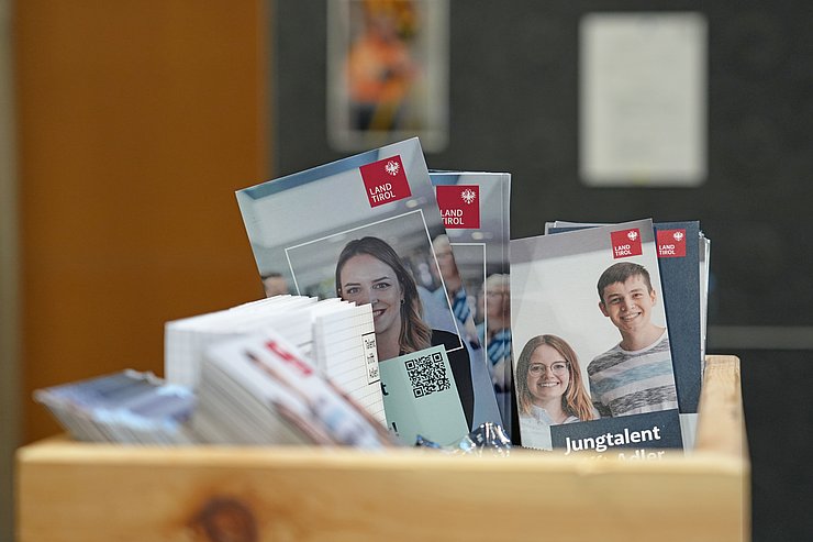 Broschüren befinden sich in einer Holzbox.