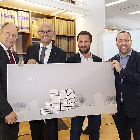 Von links: Vereinsobmann Franz Pegger, LH Anton Mattle, Hochbaureferent LHStv Georg Dornauer und Ferdinandeums-Direktor Karl C. Berger stehen mit einem Bild des neuen Ferdinandeums vor einem Bücherregal