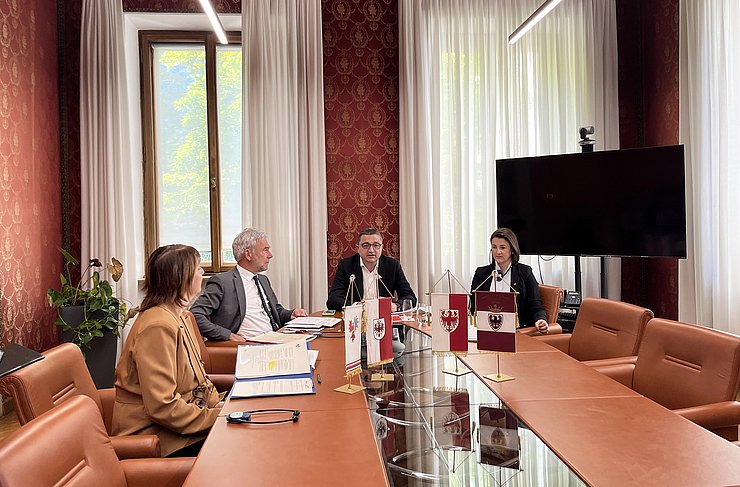 © Presseamt Trentino Landesrätin Astrid Mair (rechts), der Landeshauptmann von Trentino Maurizio Fugatti (mitte) und Landesrat Arno Schuler aus Südtirol sitzen an einem Tisch und präsentieren das neue Abkommen zur Zusammenarbeit im Zivil- und Katastrophenschutz.