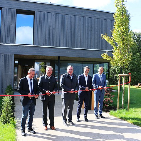 Gruppe schneidet rotes Band zur Eröffnung des Neubaus