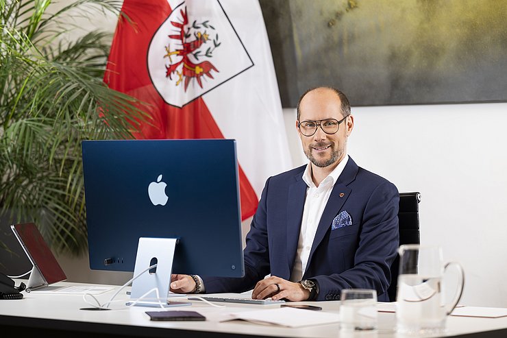 © Land Tirol/Die Fotografen LR Mario Gerber in seinem Büro vor einem Computerbildschirm.