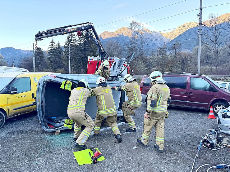 Ein Auto liegt seitlich und wird von Feuerwehrleuten bearbeitet. 