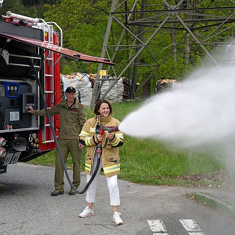 Mair neben Auto mit Schlauch; spritzt Wasser