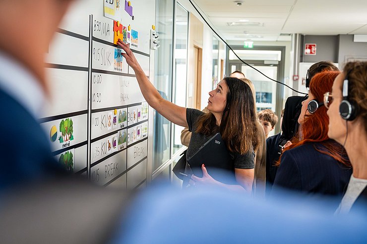 © Land Tirol/Christanell Frau zeigt etwas auf Tafel und erklärt; mehrere Personen mit Kopfhörer sehen ihr zu