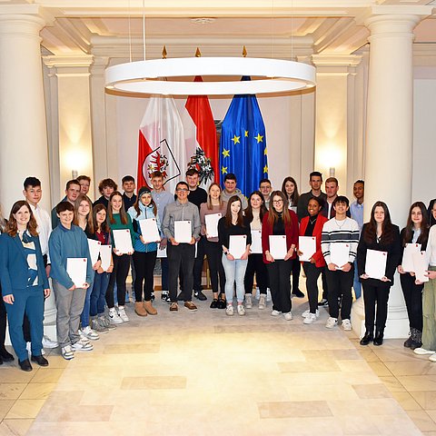 Gruppenfoto mit dem Landeshauptmann, den Mitarbeiterinnen der Abteilung Organisation und Personal sowie den Lehrlingen in der Säulenhalle vor den Büroräumlichkeiten des Landeshauptmanns.
