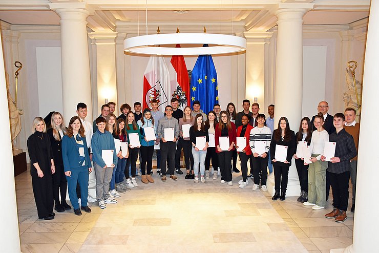 Gruppenfoto mit dem Landeshauptmann, den Mitarbeiterinnen der Abteilung Organisation und Personal sowie den Lehrlingen in der Säulenhalle vor den Büroräumlichkeiten des Landeshauptmanns.
