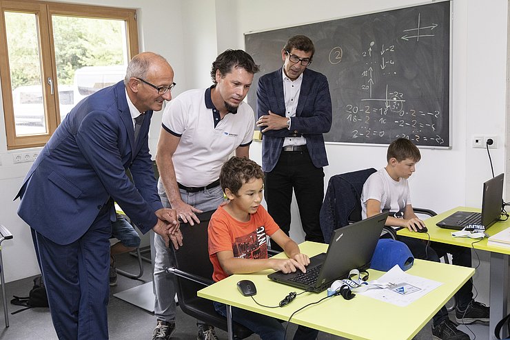 © Land Tirol/Die Fotografen LH Mattle schaut mit den Leitern des Kurses Coding4kids den Kindern beim Programmieren zu.