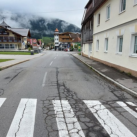 Foto einer beschädigten Straße mit Zebrastreifen und Gehsteig im Orstkern