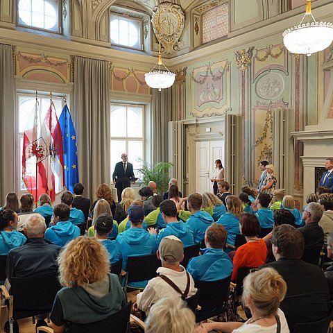 Parissaal im Landhaus mit Menschen sitzend; LH Mattle redend an Podium