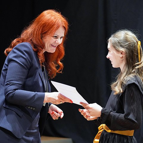 Landesrätin Hagele überreicht einem Mädchen eine Urkunde.