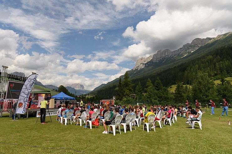 Die Jugendlichen sind vor einer Bühne auf Stühlen versammelt. Es treten die berühmten AthletInnen der Staatspolizei-Sportgruppe „Fiamme Oro“ auf. 