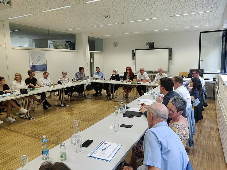 Foto aus Besprechungsraum; Menschen sitzen um Tische