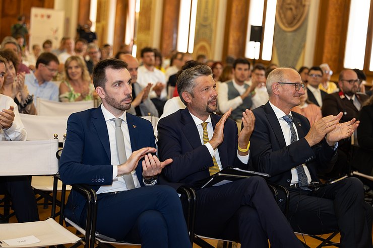 © Landespresseamt Trient Personen sitzen nebeneinander, klatschen