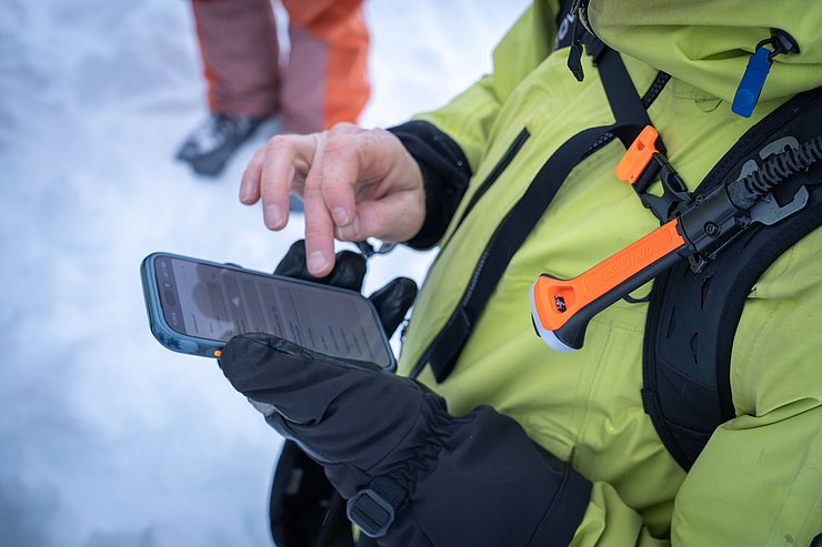 Mann im Schnee bedient Smartphone