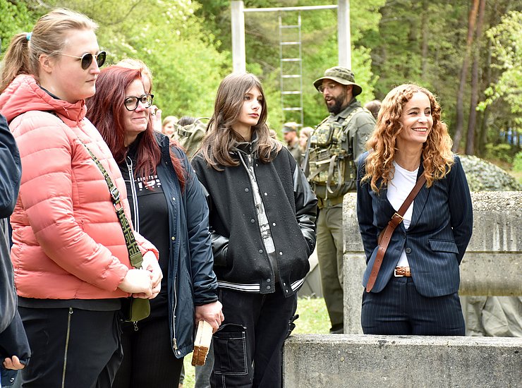 Eine Frau und mehrere Mädchen stehen im Freien bei einem Hindernisparcours.