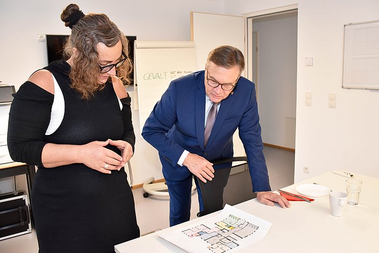 Plattner und LH Platter beugen sich über einen farbigen Bauplan